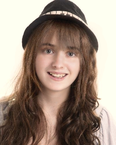 headshot of Emily Kelly wearing a music motif hat